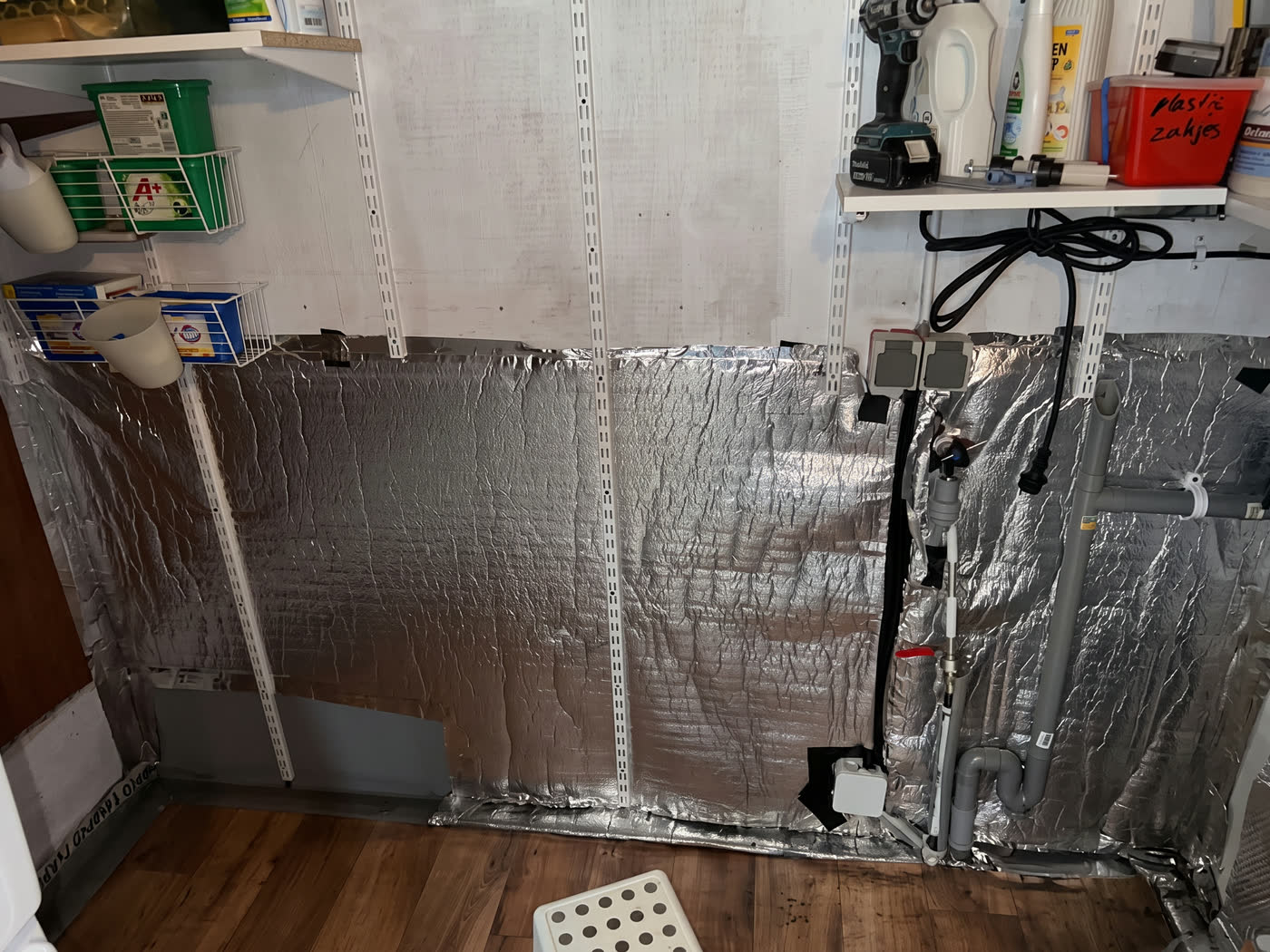 Isolatiefolie aangebracht op de wand van een bergruimte, met nieuwe bekabeling en leidingwerk erlangs
