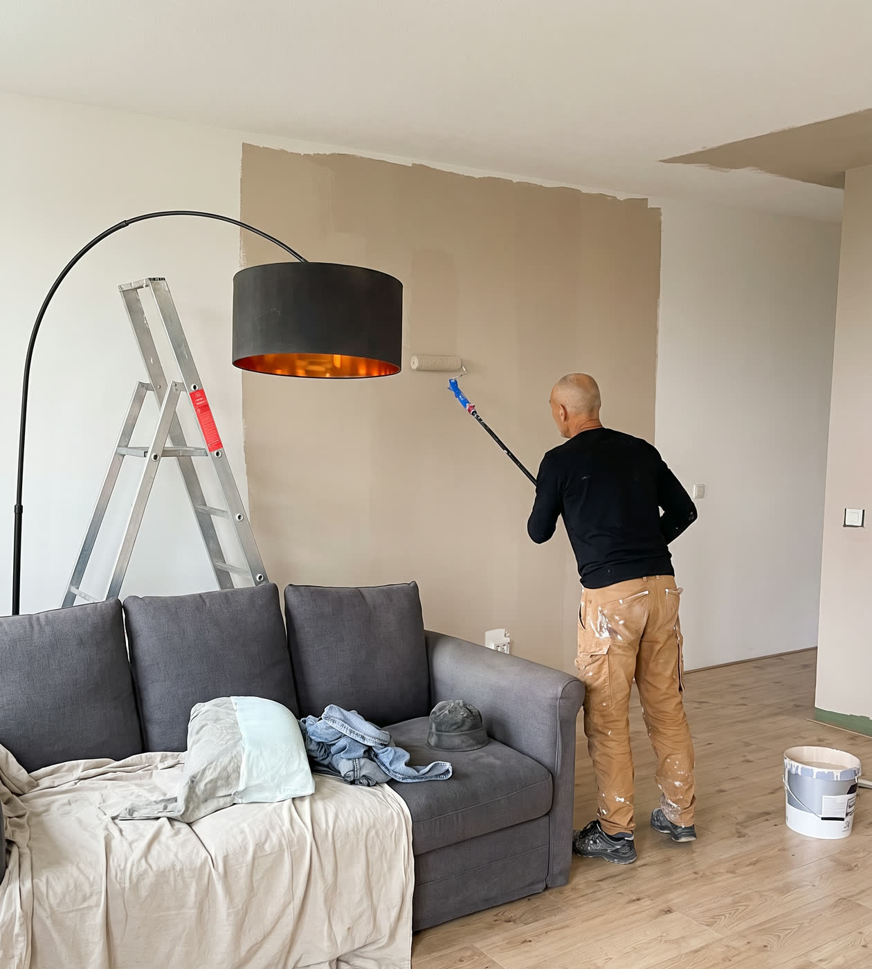Vakman van MA Klussen &amp; Onderhoud rolt een wand in tijdens een schilderklus in een appartement